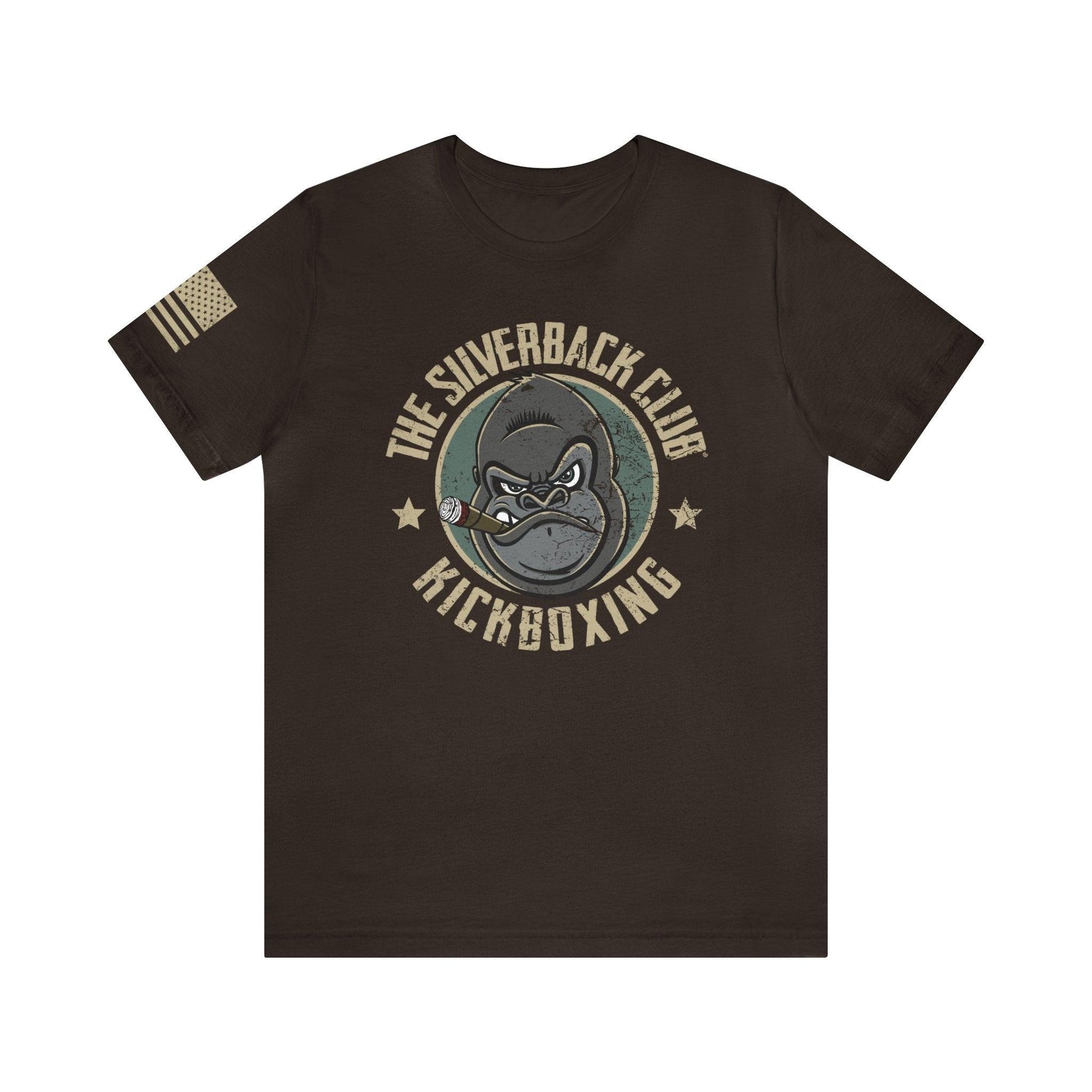 The front of a brown t-shirt and The Silverback Club logo consisting of a gorilla's face smoking a cigar and the words "Kickboxing" underneath. The U.S. flag is on the right sleeve.