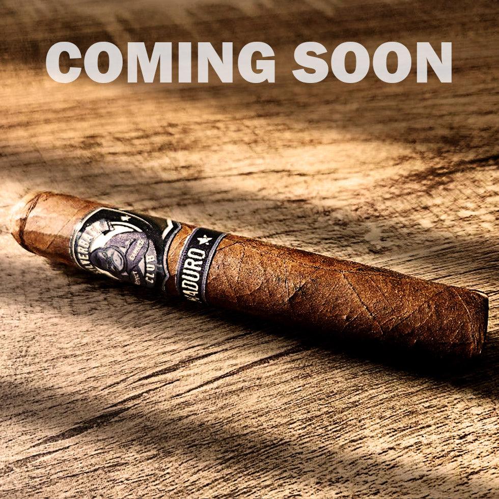 A cigar with a wrapper that has The Silverback Club logo on it of a gorilla smoking a cigar with the words "Maduro". The words "Coming Soon" are over top of the cigar.