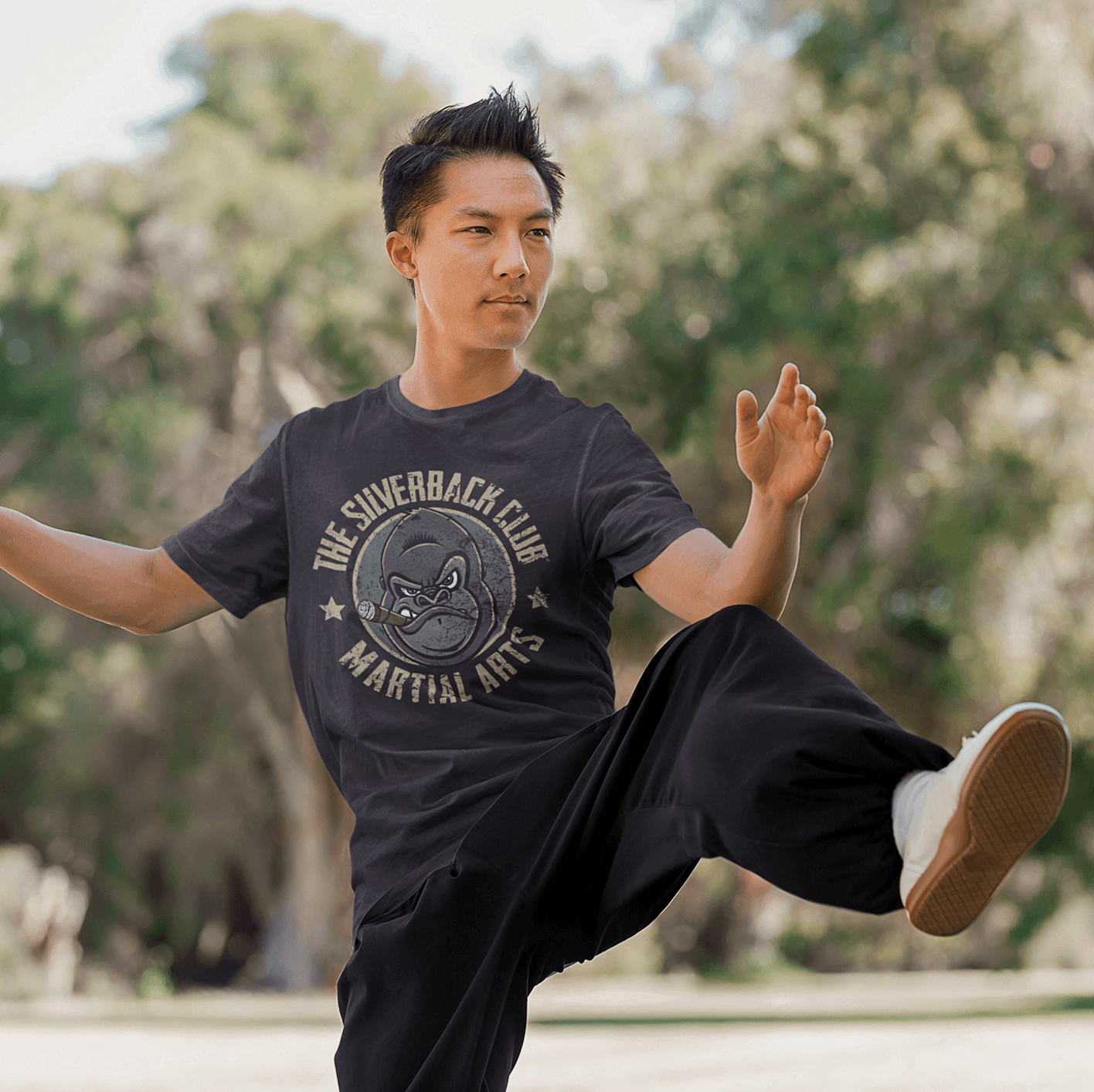 The front of a vintage black t-shirt and The Silverback Club logo consisting of a gorilla's face smoking a cigar and the words "Martial Arts" underneath. The man is practicing his katas.