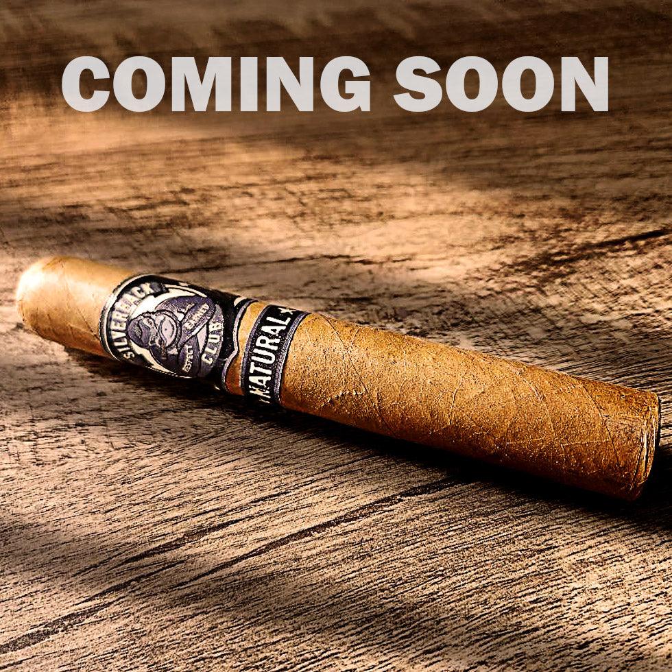 A cigar with a wrapper that has The Silverback Club logo on it of a gorilla smoking a cigar with the words "Natural". The words "Coming Soon" are over top of the cigar.